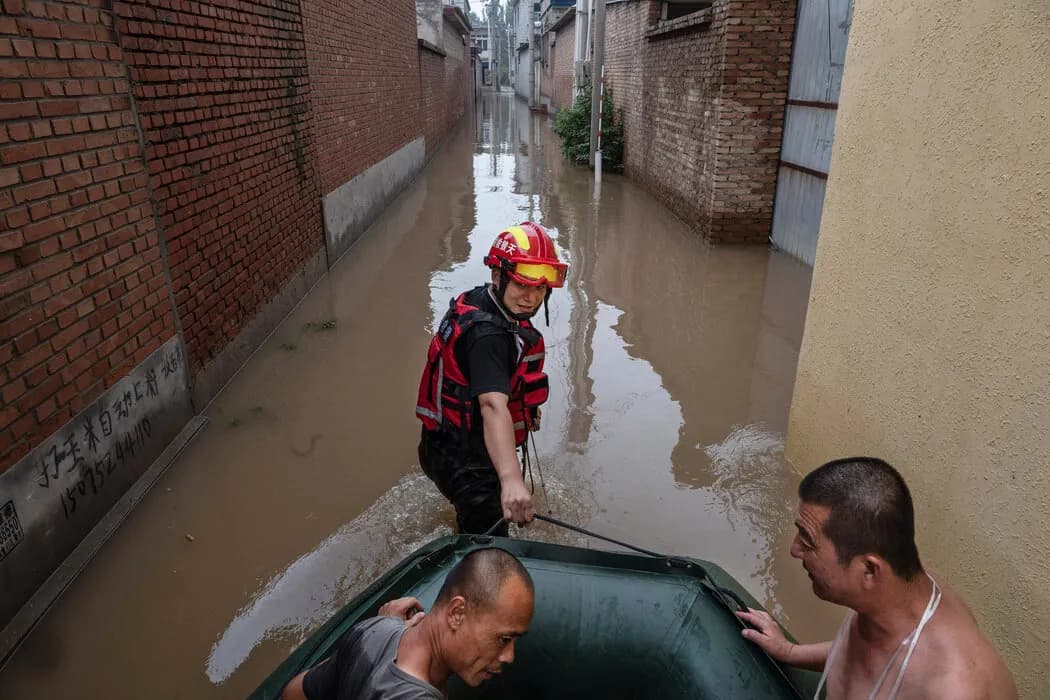 周四，一名救援人员在涿州附近拉着一艘载有居民的船只。 Kevin Frayer/Getty Images