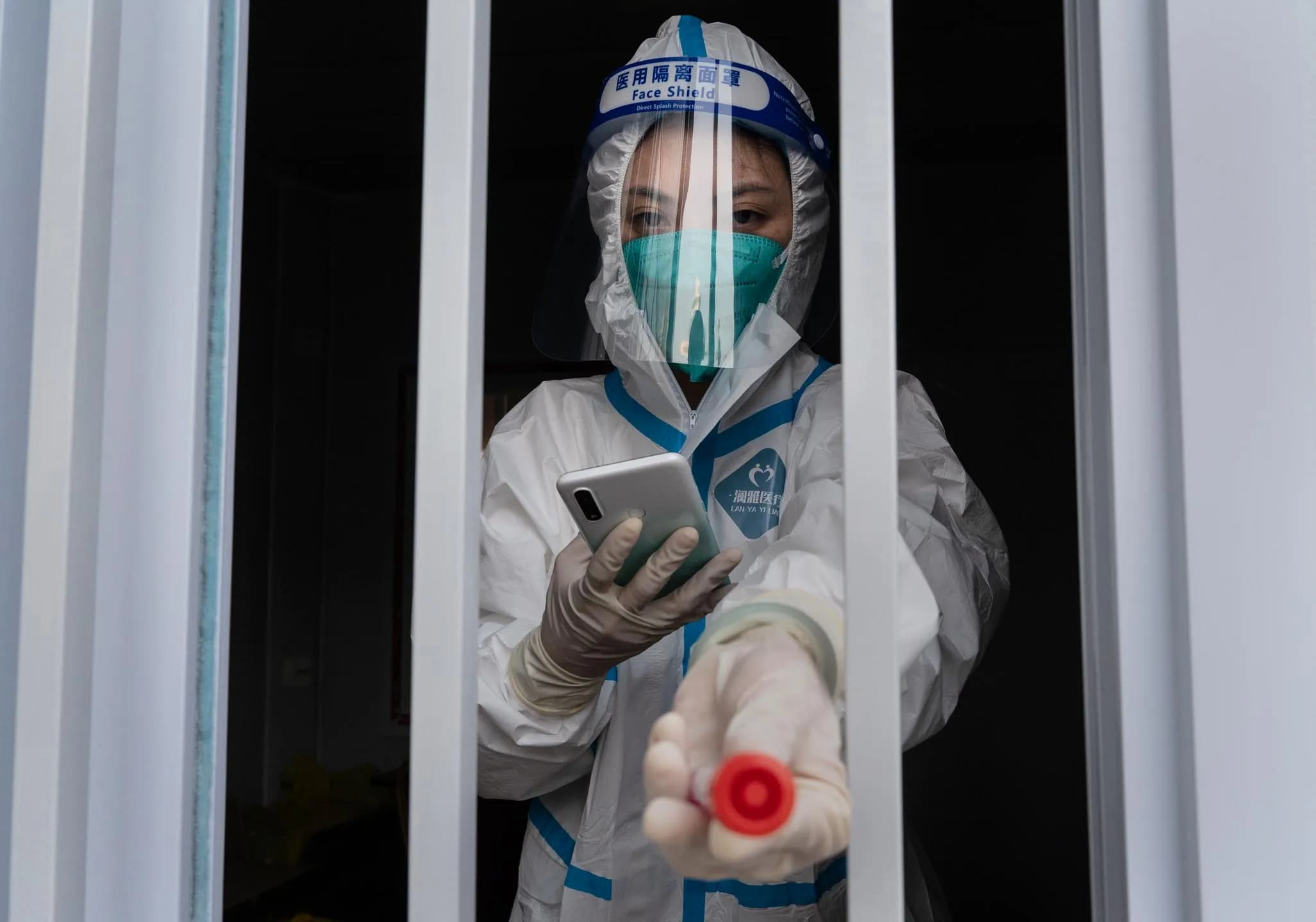 2022 年 10 月 14 日，中国北京，一名健康检测人员拿著用于核酸检测的瓶子。摄：Kevin Frayer/Getty Images