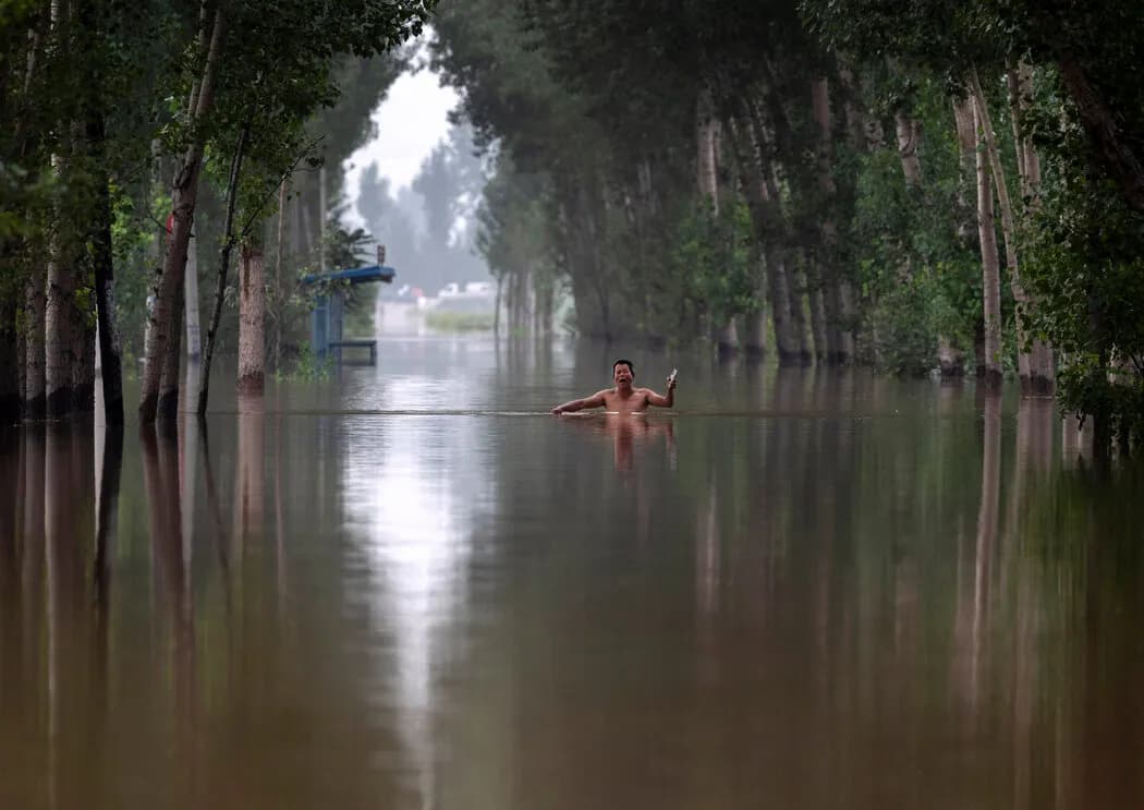 一位居民在涿州附近齐胸深的洪水中行走。 Kevin Frayer/Getty Images