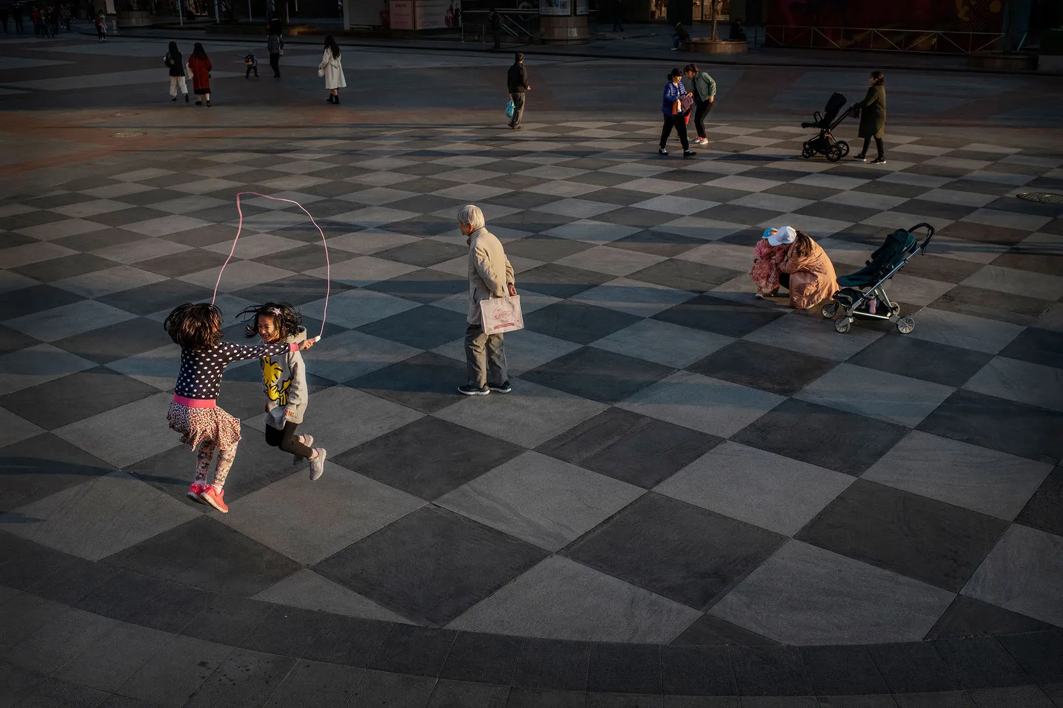 2019 年 11 月 8 日，中国北京，两名孩子在购物中心外跳绳。摄：Kevin Frayer/Getty Images
